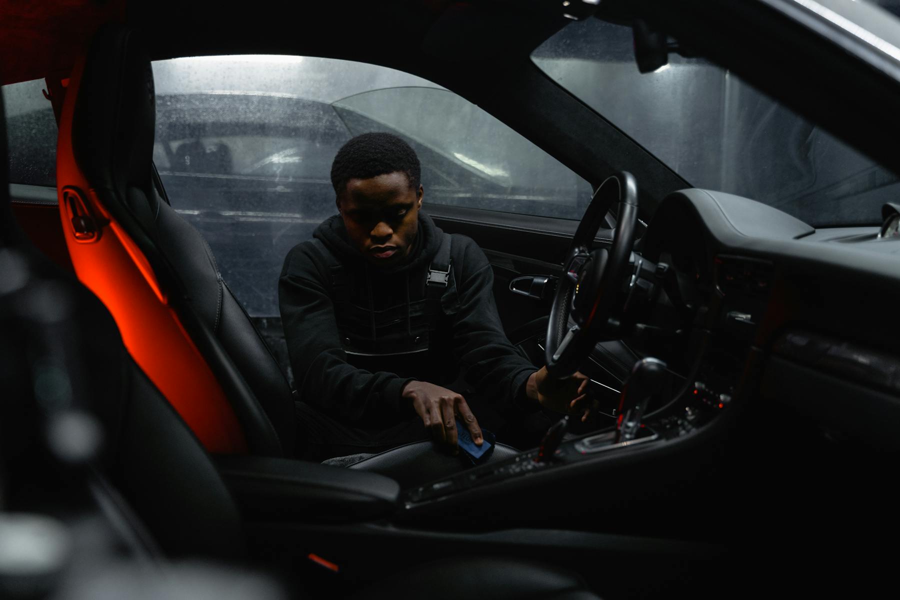 Detailer cleaning a dark vehicle interior