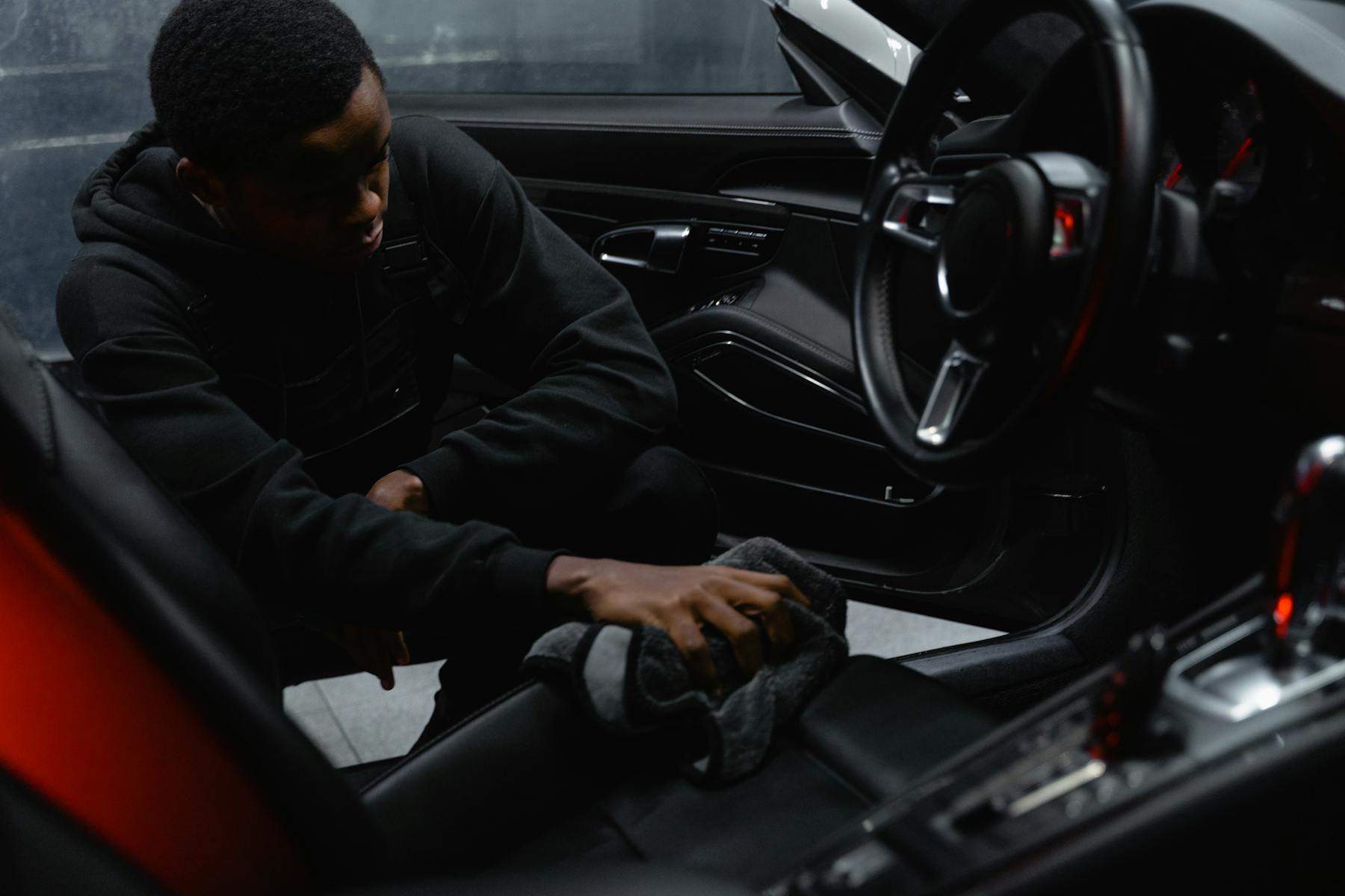 Detailer wiping leather seats inside a car